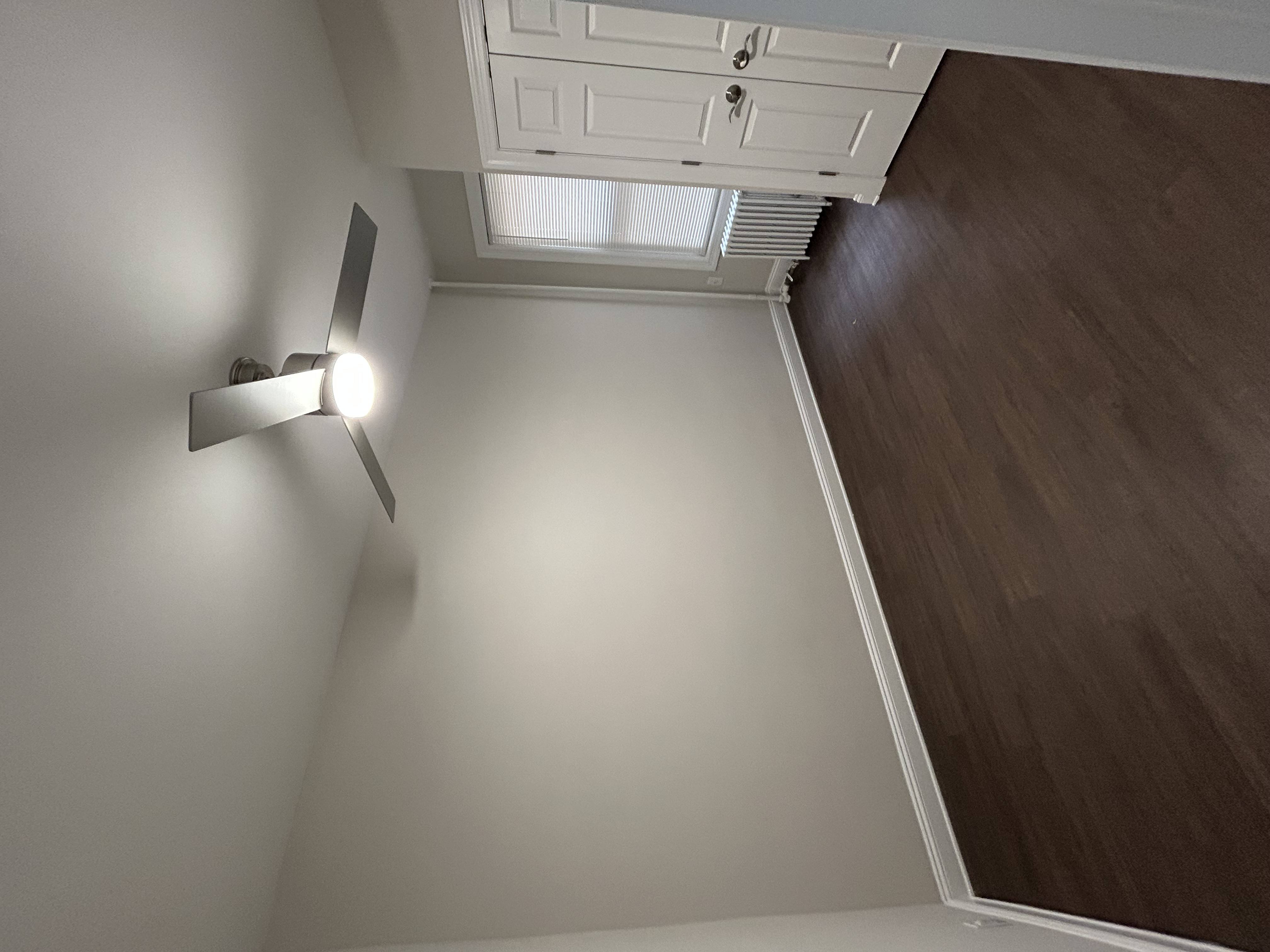 A wall-mounted light fixture is on the left side of a white wall.